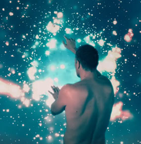 Ivan Segreto a mezzo busto di spalle e nudo gioca con le stelle del cosmo
